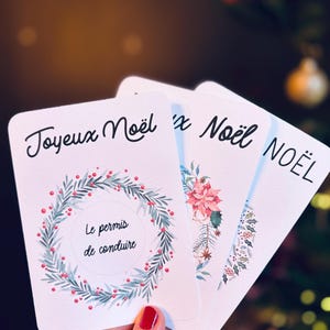 May include: Four white cards with Christmas greetings in French. The top card has a wreath with red berries and green leaves and the text 'Joyeux Noël' and 'Le permis de conduire'. The second card has a pink flower and the text 'x Noël'. The third card has a green and red floral design and the text 'NOËL'.