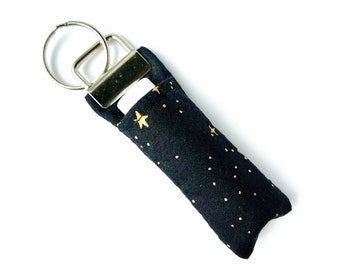 Portachiavi con balsamo per labbra / Tessuto con stelle metalliche nere e dorate di Rifle Paper Co.