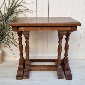 Op de afbeelding: Een houten nesttafel met drie niveaus. De tafel is gemaakt van donker hout en heeft een eenvoudig, klassiek ontwerp.