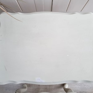 May include: A white painted table with a scalloped edge and a distressed finish. The table has a simple design and is perfect for a small space.