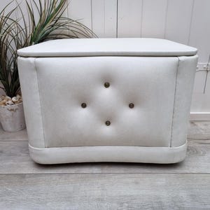 May include: White tufted storage ottoman with a diamond pattern and button accents.