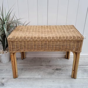 Peut inclure: Un banc en osier tressé naturel avec un dessus rectangulaire et quatre pieds. Le banc est en osier brun clair et a une finition naturelle.