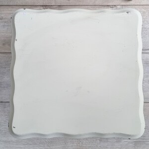 May include: White painted wooden tray with a scalloped edge. The tray is made of wood and has a distressed white paint finish.