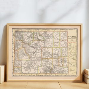 Pode incluir: Mapa vintage emoldurado do Wyoming, com informações geográficas detalhadas. O mapa é impresso em papel envelhecido, com fundo bege e linhas pretas e coloridas. O mapa está emoldurado em uma moldura de madeira clara.