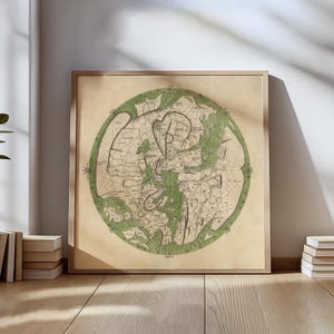 May include: A framed vintage map print. The map is circular, with a green border and intricate lines and symbols in the center. The background is a tan colour, and the frame is a light brown. The print is displayed on a wooden floor.