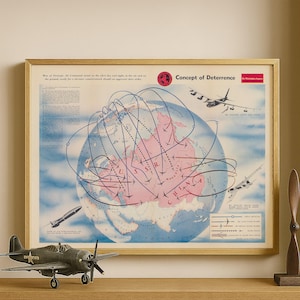 May include: A framed vintage map titled "Concept of Deterrence" with a globe graphic and flight paths. A model airplane and a wooden propeller are in front of the frame. The map is in a gold frame and sits on a wooden shelf.