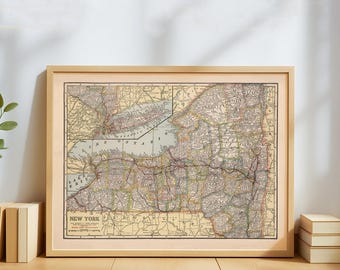 May include: Framed vintage map of New York State, featuring detailed cartography in muted tones of beige, green, and brown. The map is enclosed in a light wooden frame, with the title "NEW YORK" at the bottom.