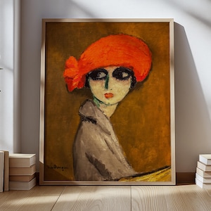 Può includere: Una stampa artistica incorniciata di una donna con un cappello rosso. Il dipinto raffigura una donna con occhi scuri, labbra rosse e un cappotto grigio. Lo sfondo è di colore marrone caldo. L'opera d'arte è esposta su un pavimento in legno con libri.
