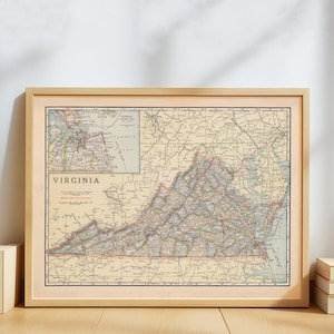 May include: Framed vintage map of Virginia, featuring detailed roads, cities, and geographical features. The map is in a light wood frame, with the word "VIRGINIA" prominently displayed. The map has a beige and brown color scheme.