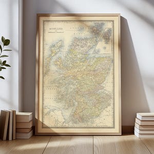 May include: A framed vintage map of Scotland, showing detailed geographical features. The map is in a wooden frame and is displayed on a wall. The map's colours include beige, brown, green, and yellow. The word "SCOTLAND" is at the top of the map.