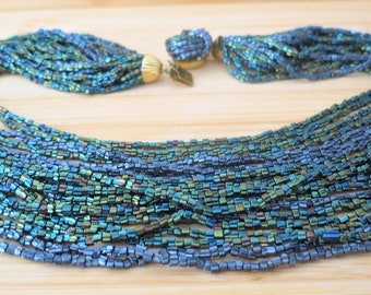 A vintage multi stranded peacock glass necklace with gold tone fastenings and decorative clasp