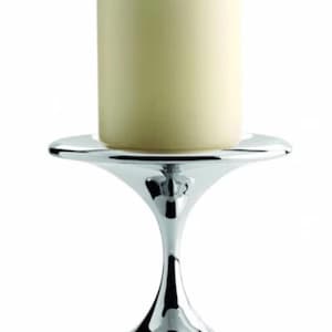 May include: A polished chrome candle holder with a wide base and a flared, hourglass-shaped stem. A cream-coloured pillar candle sits atop the holder. The candle holder is designed to hold a single candle and is suitable for home decor.