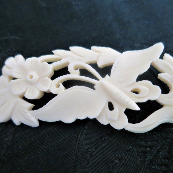 A dainty antique moulded celluloid brooch featuring flowers and a butterfly