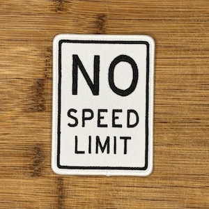 May include: White square patch with black text that reads "NO SPEED LIMIT".