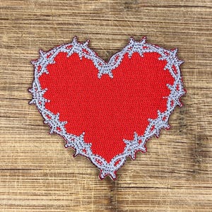 May include: Red heart-shaped patch with a silver barbed wire border.
