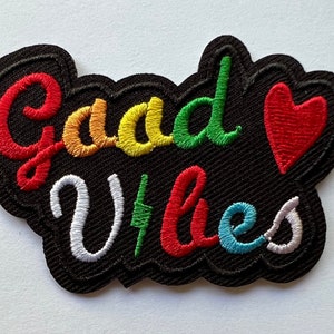 May include: Embroidered patch with the words "Good Vibes" in rainbow colors and a red heart. The patch is on a black background.