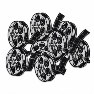 Loose pile of black and white embroidered film reel patches layered together on a square white background.