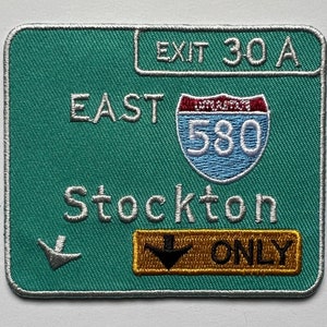 Könnte beinhalten: Grünes Straßenschild mit weißem Text und Rand. Das Schild zeigt "Ausfahrt 30A Ost Interstate 580 Stockton Nur". Ein weißer Pfeil zeigt nach unten rechts.