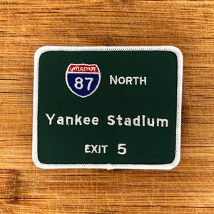 Op de afbeelding: Groen en wit geborduurd patch met een snelweg bord voor Interstate 87 North, afslag 5 voor Yankee Stadium.