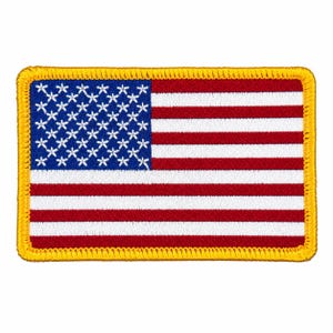 May include: A rectangular embroidered patch featuring the flag of the United States of America. The design includes a blue canton with white stars and alternating red and white horizontal stripes, all enclosed by a thick, bright yellow border.