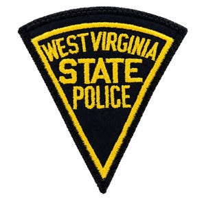 May include: A triangular embroidered patch with a black background and a yellow border. The text WEST VIRGINIA STATE POLICE is stitched in yellow capital letters across the centre of the patch. The edges are finished with black thread.