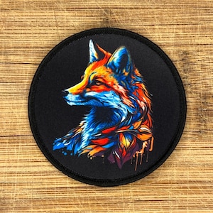 Op de afbeelding: Ronde zwarte patch met een kleurrijke vosillustratie. De vos is in profiel afgebeeld met levendige oranje, blauwe en rode tinten. De patch heeft een zwarte rand en is waarschijnlijk een opstrijk- of opnaaipatch.