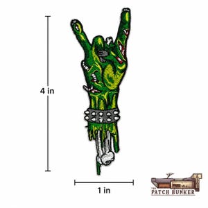 Zombie hand embroidered patch size reference graphic showing a green monster hand making a rock gesture, with studded bracelet, exposed bone, black measurement lines, and Patch Bunker logo on a clean white background.