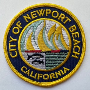 May include: A yellow and blue embroidered patch with the text "City of Newport Beach California". The patch features a stylized image of sailboats and fish.