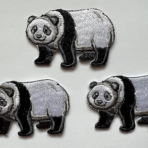 Może przedstawiać: Trzy haftowane naszywki z czarno-białymi pandami. Pandy stoją z widocznymi łapami. Naszywki mają około 5 cm.