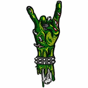Zombie hand embroidered patch size reference graphic showing a green monster hand making a rock gesture, with exposed bone, torn details, studded bracelet, and a 4x1 inch measurement on a clean white background.