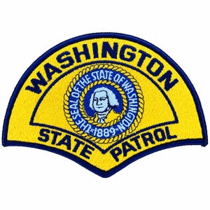 Può includere: Una toppa ricamata a forma di semicerchio con sfondo giallo e bordo blu scuro. Il testo WASHINGTON è arcuato in alto e STATE PATROL è in basso. Al centro si trova il sigillo circolare dello Stato di Washington.