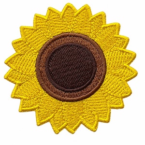 May include: A circular embroidered patch featuring a sunflower design. The center is a solid dark brown circle surrounded by a ring of lighter brown stitching. The outer edge consists of numerous pointed, bright yellow embroidered petals.
