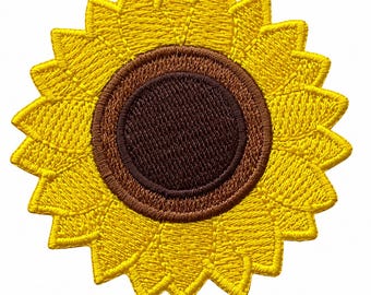 Pode incluir: Um emblema bordado circular com um design de girassol. O centro é um círculo castanho escuro sólido rodeado por um anel de costura castanho mais claro. A borda externa consiste em inúmeras pétalas pontiagudas bordadas em amarelo vivo.