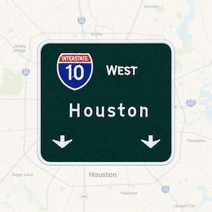 May include: A square embroidered patch featuring a dark green background with a white border. It displays a blue and red Interstate 10 shield, the text WEST, the word Houston in white, and two white downward-pointing arrows at the bottom corners.