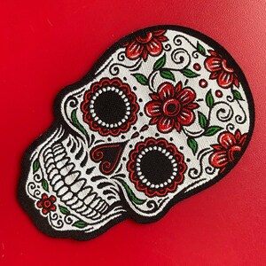 Red and black floral sugar skull embroidered patch on red background, Day of the Dead design.