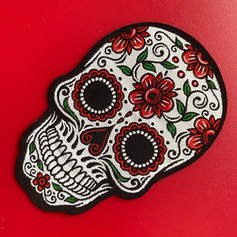 Red and black floral sugar skull embroidered patch on red background, Day of the Dead design.