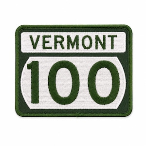 May include: A rectangular embroidered patch featuring a dark green border and background. The top section contains the white text VERMONT in dark green. The bottom section displays the large dark green number 100 on a white background.