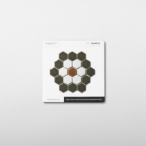 May include: A sample card featuring a mosaic tile design. The tiles are arranged in a floral pattern, with a central brown tile surrounded by white, olive green, and dark green hexagonal tiles. The card includes the text "SAMPLE" and "CEMENTO".