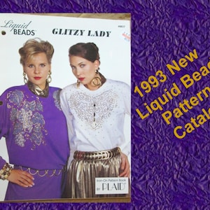 May include: A catalog cover featuring two women modeling beaded clothing. The cover reads "1993 New Liquid Beads Pattern Catalog" with the "Liquid Beads" and "Glitzy Lady" logos. The women are wearing embellished tops and gold accessories.