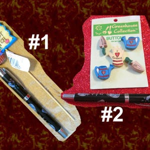May include: Two pens with black barrels and silver accents. One pen is next to a wooden sign that says "Carrot Patch" and a cupcake. The other pen is next to a card with gardening-themed buttons.