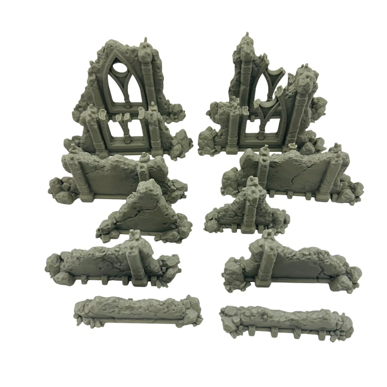 May include: A collection of gray miniature ruined structures, including archways, walls, and debris. The pieces are designed to resemble weathered stone, suitable for tabletop gaming or model building. The set includes various sizes and shapes.