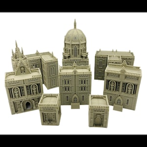 May include: A collection of unpainted beige miniature buildings for tabletop gaming, featuring gothic architectural details like arched windows, skull motifs, stone textures, and a central structure topped with a large dome.