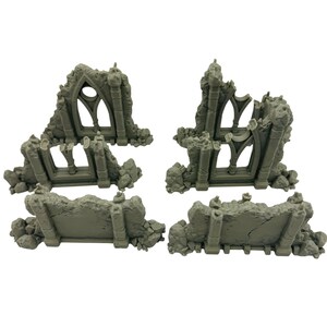 May include: Four gray miniature ruined structures, likely for tabletop gaming or model building. The pieces include sections of arched windows and crumbling walls, with a weathered, stone-like texture. The pieces are arranged on a white background.