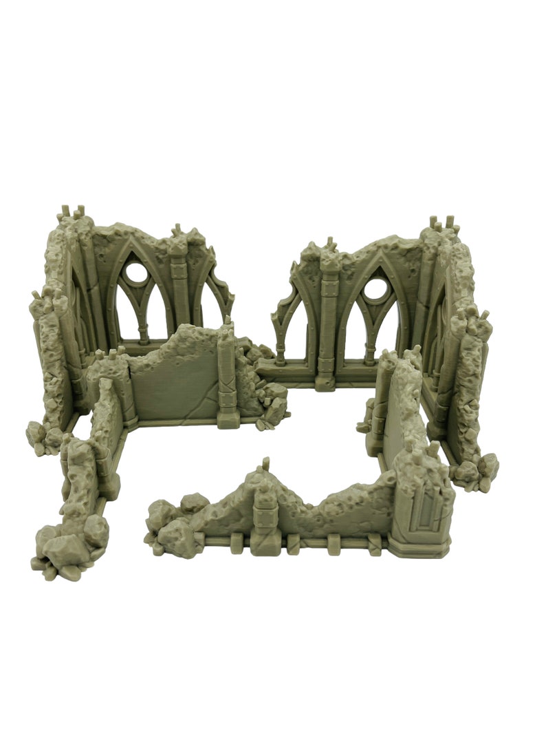 May include: A light gray, unpainted miniature terrain piece depicting the ruins of a stone building. The structure features jagged, broken walls, remnants of gothic-style arched windows with circular openings, and textured rubble details.