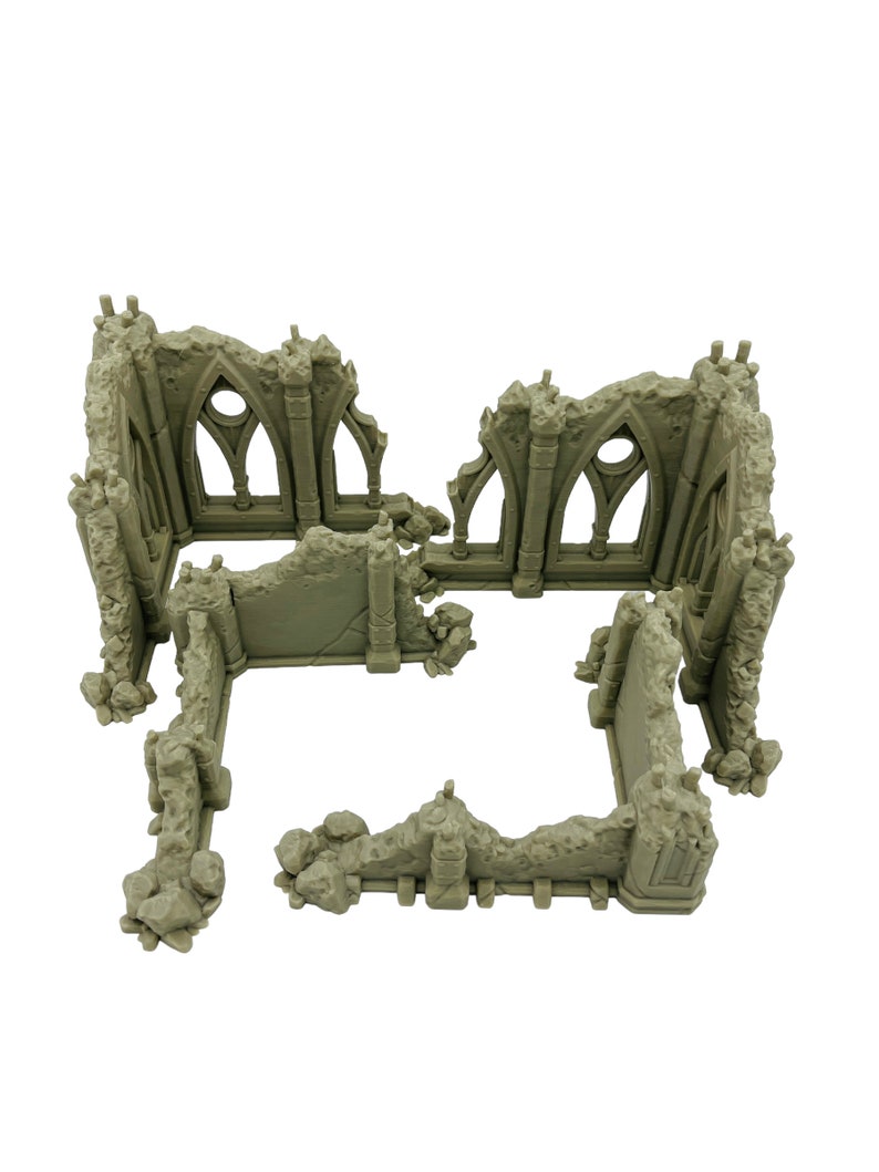 May include: A light gray miniature model of a ruined stone building with jagged edges, crumbling walls, and arched window frames. The structure features weathered textures and broken pillars, designed as a tabletop gaming terrain piece.