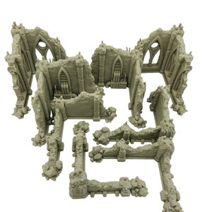 May include: A set of unpainted light gray miniature terrain pieces depicting ruined stone walls and gothic architectural structures with arched windows, textured rubble, and integrated mechanical details for tabletop gaming.