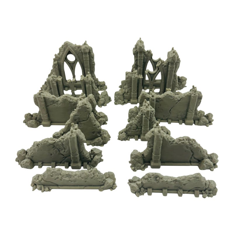 May include: A set of gray miniature ruined structures, including sections of walls and archways. The pieces are designed to resemble weathered stone, ideal for tabletop gaming or model building. The set includes various sizes and shapes for diverse terrain.