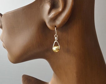 May include: A pair of gold and silver dangle earrings with a small round gold bead at the end.