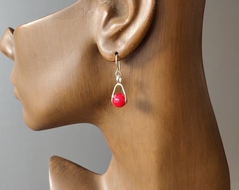 May include: Silver dangle earrings with a single red bead on each earring.