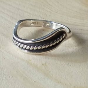 May include: A silver ring with a twisted rope design. The ring is marked with the number "925" on the inside.